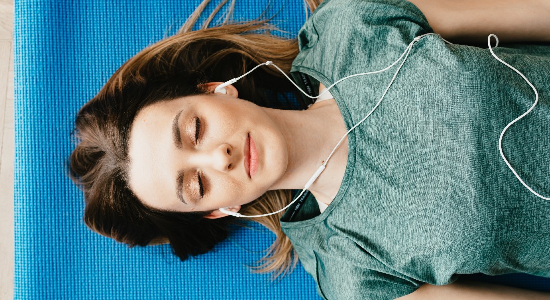 Kvinde ligger ned og lytter til musik med lukkede øjne.