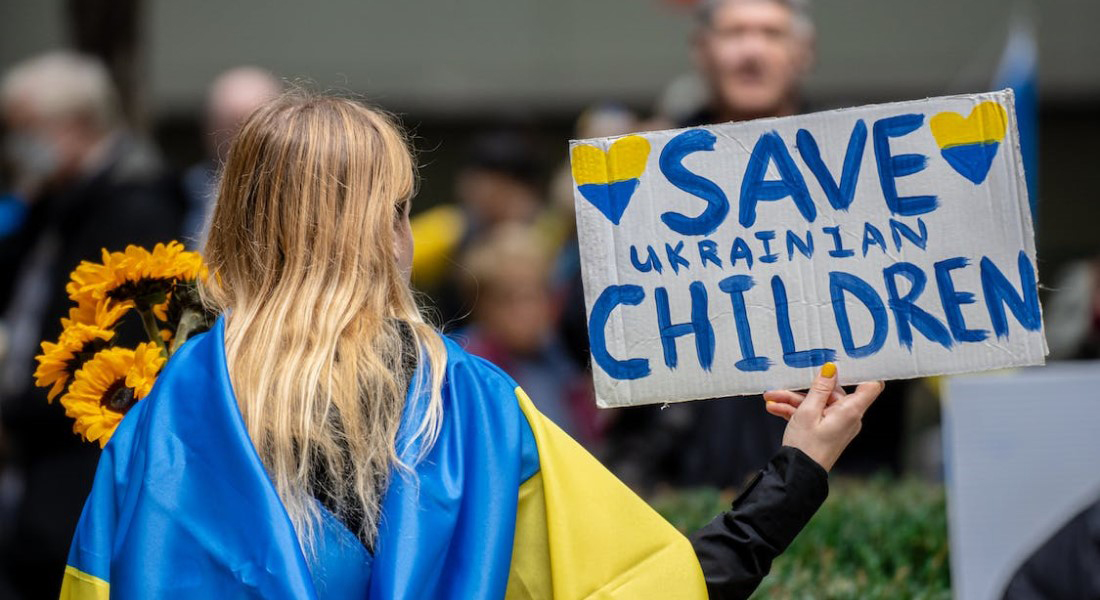 Ukrainian woman with sign saying 'Save Ukrainian Children. Photo: Derek French (Pexels)